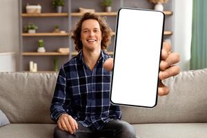 Hello Greeting. Cheerful Guy Waving Hand To Camera Sitting On Sofa At Home. Young Man Smiling And Gesturing Hi Posing Indoors. Call, Modern Distance Communication Concept photo