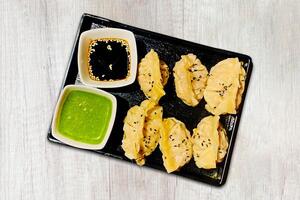 Traditional Japanese gyoza dumplings served with sauce on a black plate on a wooden background, top view photo
