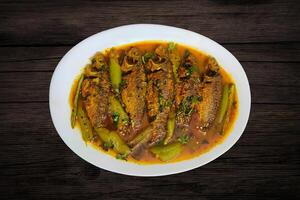 ccooked with Pointed gourd or Trichosanthes dioica vegetable on a white plate on a wooden background photo