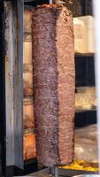 Chef skillfully cutting shawarma meat from a rotating skewer. Freshly cooked photo