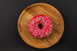 delicious donut that features vibrant red frosting and white sprinkles on top photo