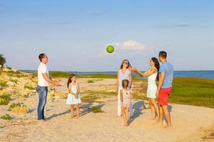 Friends with children playing with the ball on the beach photo