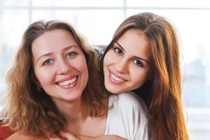 Portrait of a mother and teen daughter being close and hugging photo