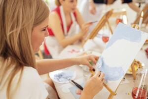 Close-up of canvas on easel and hand with spatula. Young artist paints picture at table. photo