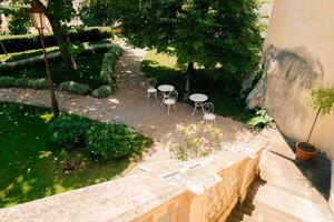 Peaceful garden terrace with chairs, tables, greenery, and colorful flowers photo