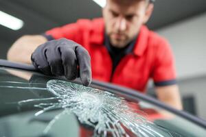 A man in a red shirt is fixing a broken windshield photo
