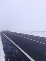 A highway with snow falling around it. Foggy and cold weather. photo