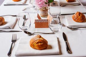 Elegant table setting with bread rolls and pink flowers centerpiece photo