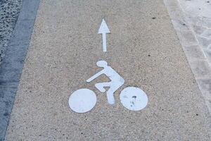 A white arrow pointing to a bicycle on a sidewalk photo
