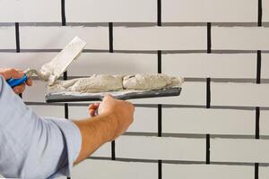 A man is using a knife to cut a tile photo