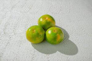 three green orange fruits on a white texture background photo