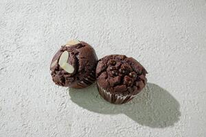 two chocolate muffins on a white surface photo