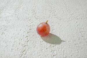 A small red fruit on a white surface photo