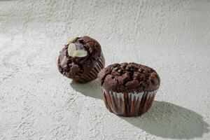 two chocolate muffins sitting on a table photo