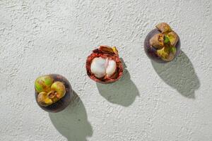 Opened mangosteen fruit revealing its white, juicy segments, set against a textured white background for a fresh, clean look photo
