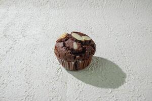 a chocolate muffin sitting on a white surface photo