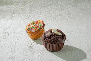 two cupcakes sitting on a table background photo