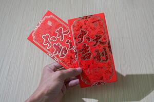 hand holding traditional red angpao used for gifting money during Chinese New Year, symbolizing good luck and prosperity photo