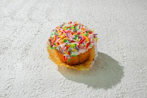 a cupcake with sprinkles on top of a white surface photo
