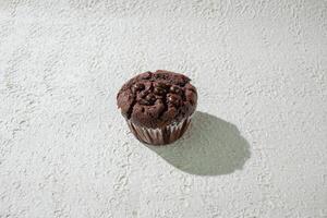 a chocolate muffin sitting on a white surface background photo