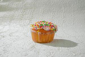 a cupcake with sprinkles on white texture background photo