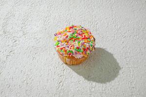 a cupcake with sprinkles on top of a white wall photo