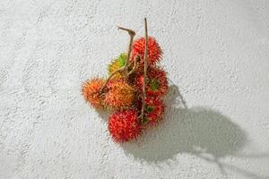 Fresh red rambutan on a textured white background, perfect as a digital asset for design projects, posters, advertisements, or creative media photo