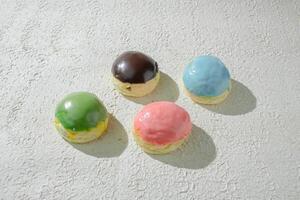 four different colored pastries or mini donuts on a white surface photo