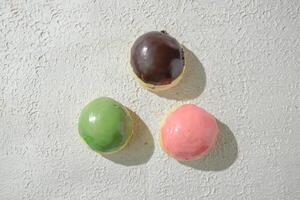 three different colored donuts on a white surface photo