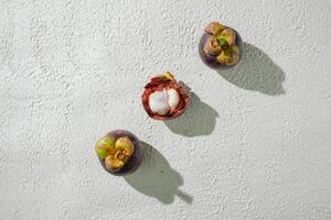 Opened mangosteen fruit revealing its white, juicy segments, set against a textured white background for a fresh, clean look. perfect for graphic asset design of fruit photo