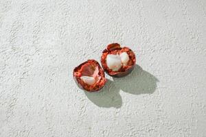 two mangosteen fruits are cut open on a white surface photo