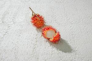 Fresh peeled two red rambutan on a textured white background, perfect as a digital asset for design projects, posters, advertisements, or creative media photo