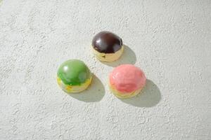 three different colored mini donuts on a white surface photo