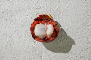 a half open mengosteen fruit on a white wall photo