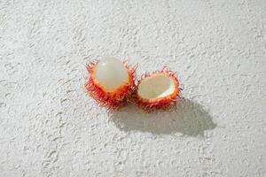 Fresh peeled one red rambutan on a textured white background, perfect as a digital asset for design projects, posters, advertisements, or creative media photo