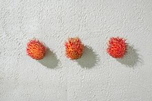 pattern of red rambutan fruit on white surface photo