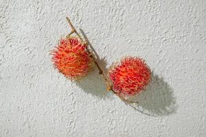 Fresh two red rambutan on a textured white background, perfect as a digital asset for design projects, posters, advertisements, or creative media photo