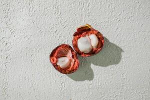 a cut open mangosteen fruit on a white surface photo