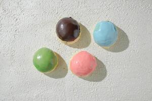 four different colored mini donuts on a white surface photo