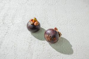 Mangosteen fruit displayed against a textured white background, emphasizing its unique purple rind and freshness. perfect for graphic asset design of fruit photo