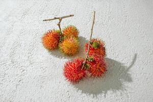 two rambutan fruits on a white surface photo