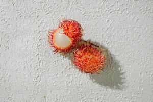 Fresh peeled red red rambutan fruit on a textured white background, perfect as a digital asset for design projects, posters, advertisements, or creative media photo