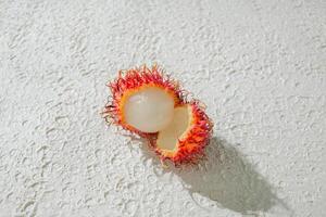 Fresh peeled red rambutan on a textured white background, perfect as a digital asset for design projects, posters, advertisements, or creative media photo