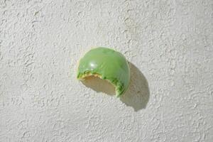 a green and white pastry or mini donut on a white wall photo