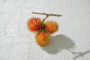 Fresh red red rambutan fruit on a textured white background, perfect as a digital asset for design projects, posters, advertisements, or creative media photo