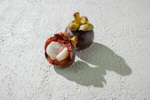 a half open mangosteen fruit on a white surface photo