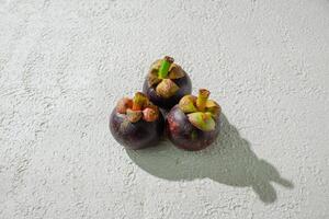 three small magosteen fruits on a white surface photo