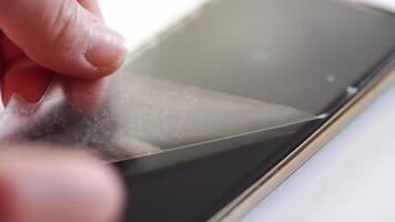 Applying protective film on smartphone display for enhanced screen durability and resistance to scratches and dust. video