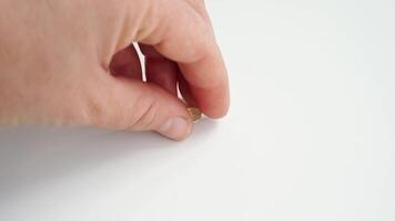 Hand dropping single capsule pill on white surface in minimalist setting. video