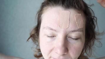 Female adult caucasian applying facial patches for forehead wrinkles in skincare routine. video